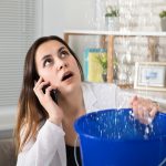 woman calling a Burbank plumber holding a bucket under leaking ceiling